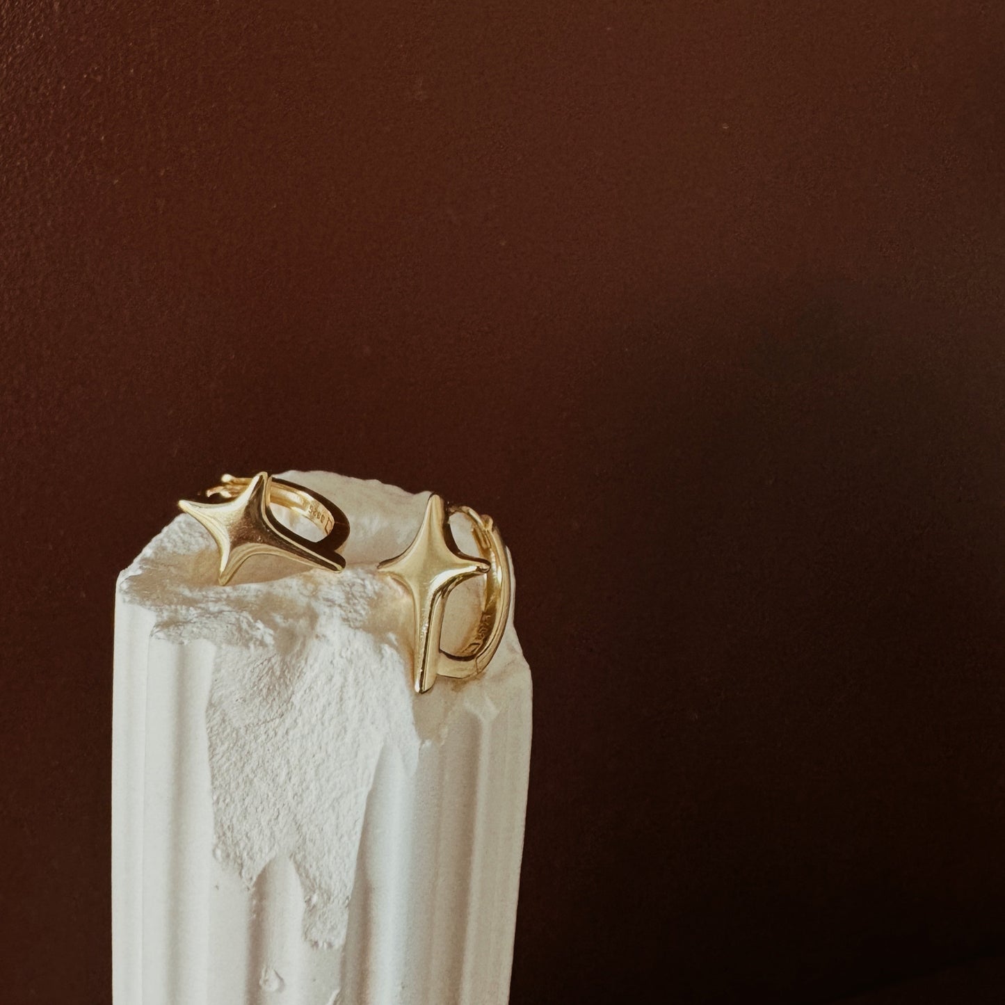 Gold hoop earrings with starburst design and polished finish